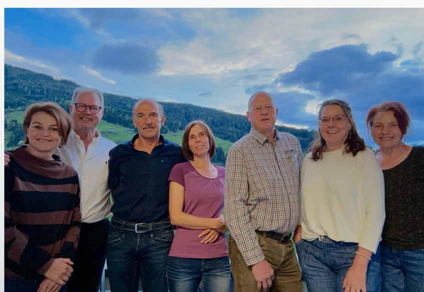 Gruppenfoto der LEWAL-Mitglieder vor einer grünen Almlandschaft mit bewölktem Himmel – Menschen hinter dem Verein.