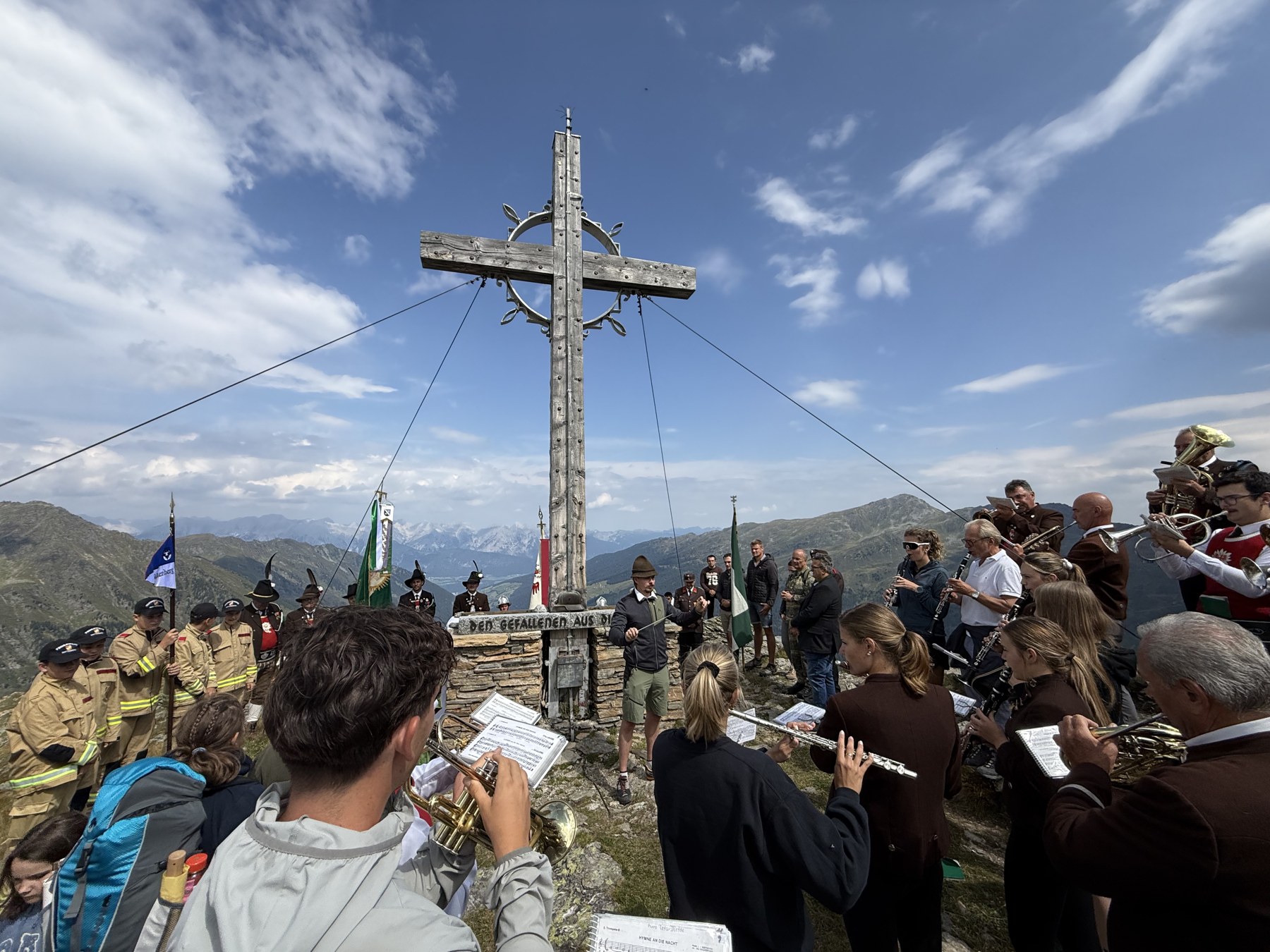 Musikkapelle und Feuerwehrjugend versammelt rund um das Gipfelkreuz beim Kriegerdenkmal am Mölsberg.